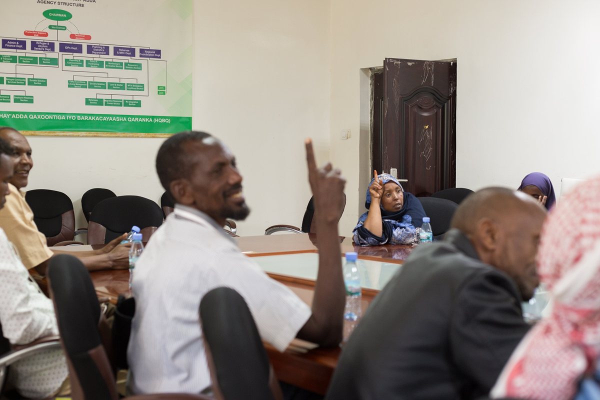 Community members raising their hands at a meeting with the authorities