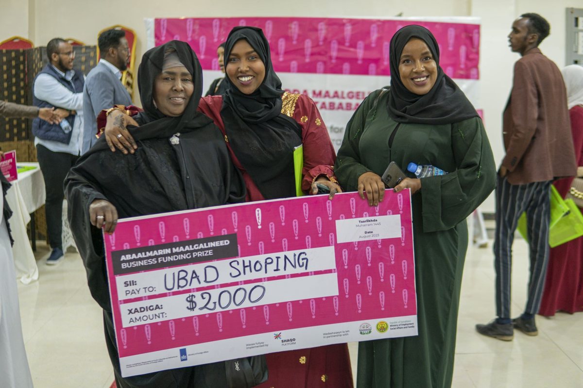 Two graduates holding their seed funding award