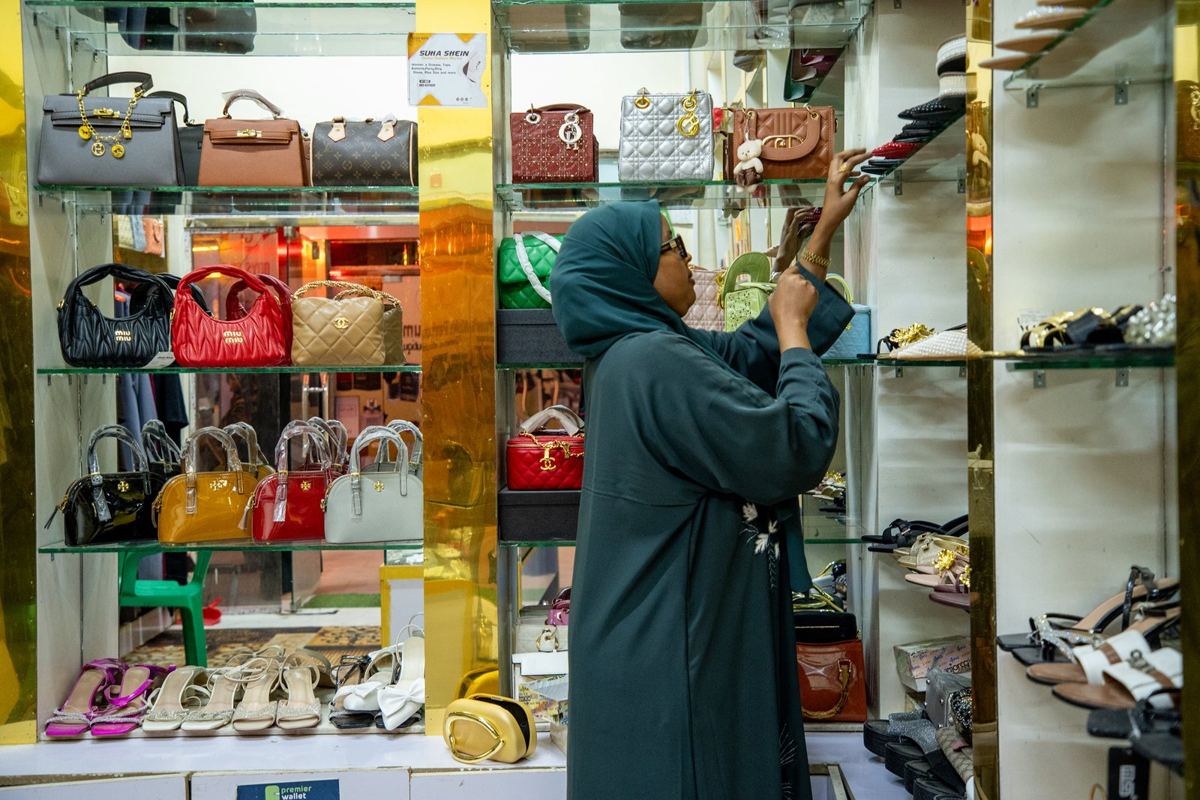 A woman arranging bags in her shop