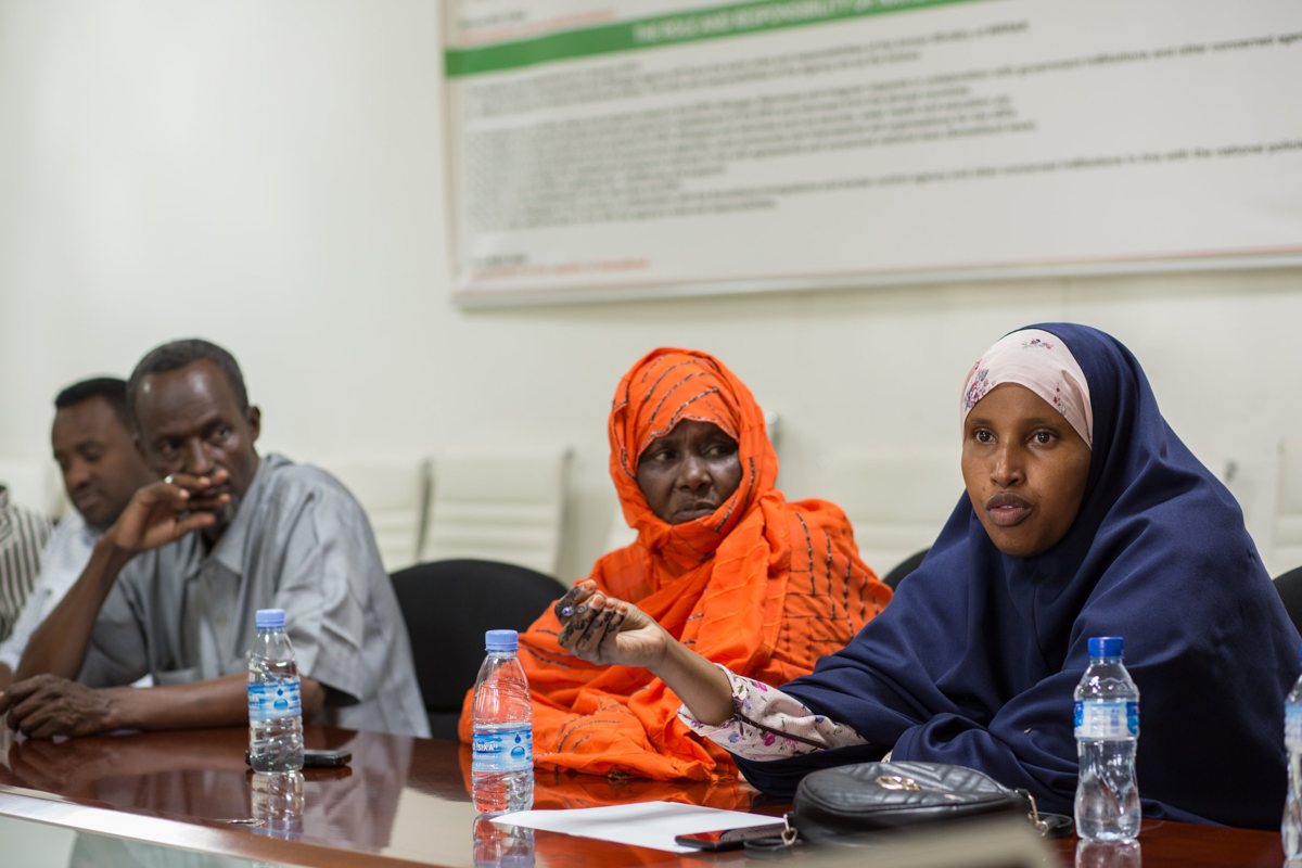 A woman speaking at a community meeting with the national refugee agency